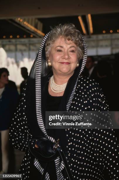 British actress Joan Plowright, wearing a black-and-white hooded outfit, attends the opening night performance of 'Ragtime' at the Shubert Theatre in...