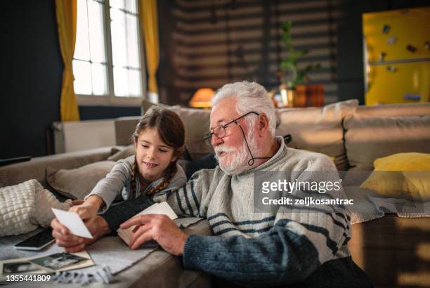 grand-père montrant à sa petite-fille des souvenirs du passé - nostalgie photos et images de collection