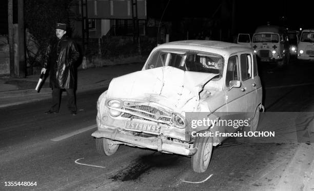 Policier et voiture Renault 4 accidentée sur la chaussée en 1975 à Paris.