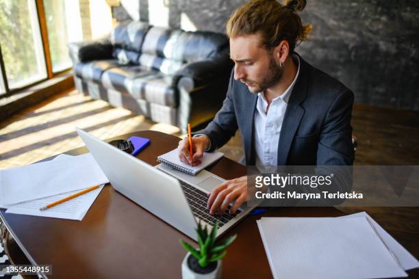 a young guy works at a laptop in a home office. - content stock-fotos und bilder