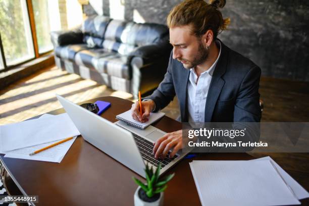 a young guy works at a laptop in a home office. - emcee stock pictures, royalty-free photos & images