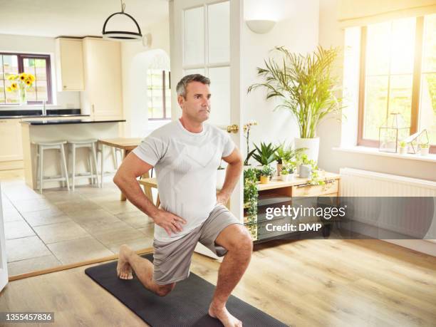 shot of a mature man doing lunges at home - lunge imagens e fotografias de stock