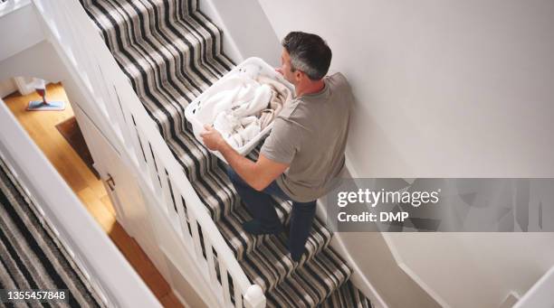 shot of a man carrying a basket of freshly laundered clothing up stairs - carrying laundry stock pictures, royalty-free photos & images