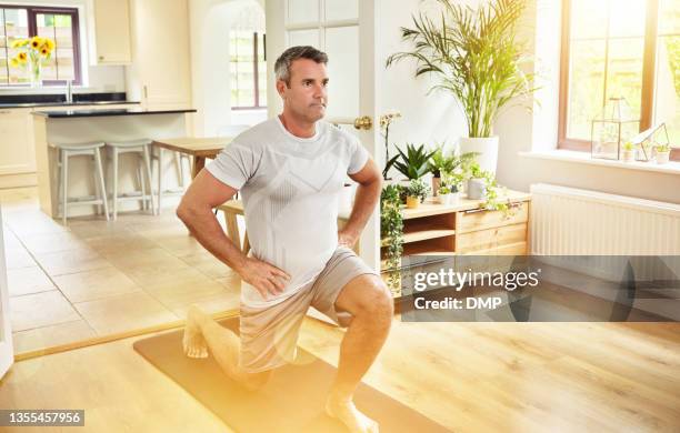 shot of a mature man doing lunges at home - lunge imagens e fotografias de stock