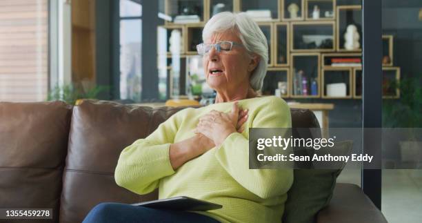 shot of a senior woman suffering from chest pain while using a digital tablet at home - gasping stock pictures, royalty-free photos & images