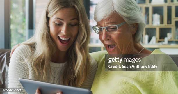 shot of a young daughter and her mother using a digital tablet at home - surprised woman looking at tablet stock pictures, royalty-free photos & images
