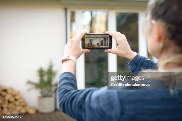 woman taking pictures of the house on a smartphone - photographing bildbanksfoton och bilder