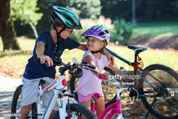 children bicycling embrace - two kids with cycle imagens e fotografias de stock