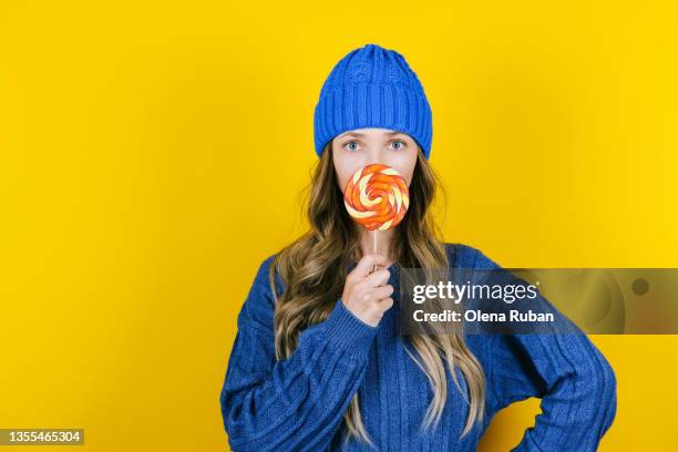 young woman hiding her mouth behind lollipop. - inviting gesture stockfoto's en -beelden