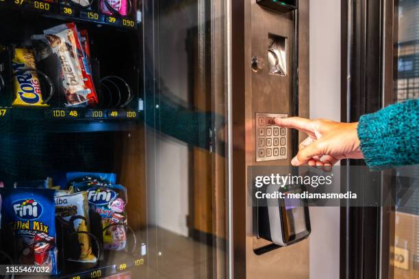 eine frau benutzt einen automaten, um essen und trinken auf der straße in valencia, spanien, zu kaufen - snacks stock-fotos und bilder