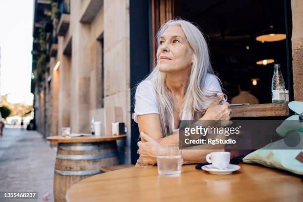 mature woman on a journey enjoying at the cafe - senior adventure stock pictures, royalty-free photos & images