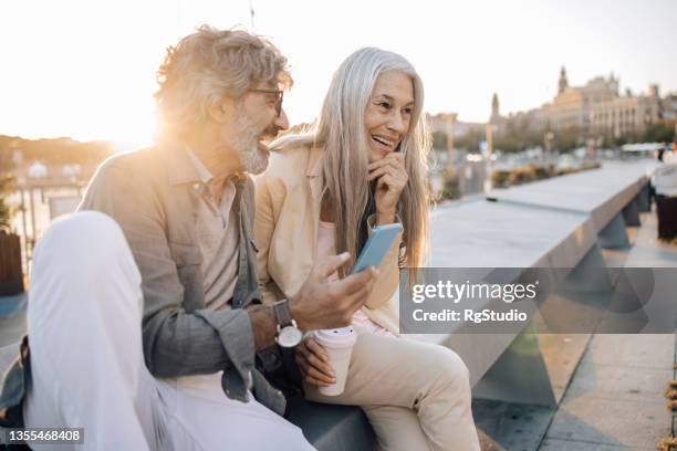 mature couple on vacation enjoying outdoors and having fun online - sixties stock pictures, royalty-free photos & images