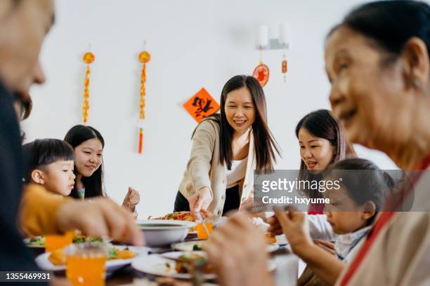 asiatische chinesische mehrgenerationenfamilie mit chinesischem silvesterabend-abendessen zu hause - chinese family stock-fotos und bilder