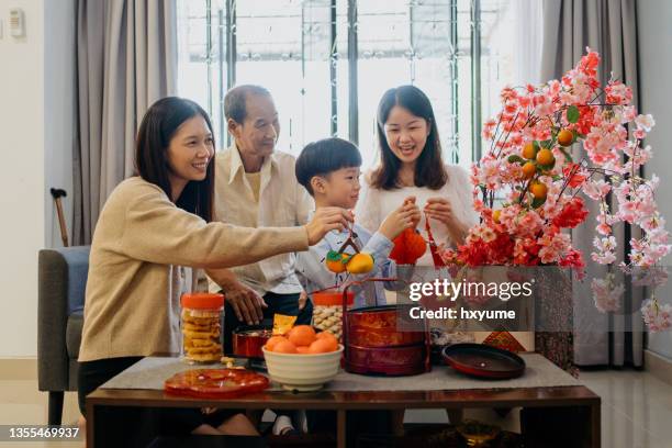 asiatische chinesische familie mit mehreren generationen, die das wohnzimmer für das familientreffen zum chinesischen neujahr schmückt - kung hei fat choi stock-fotos und bilder