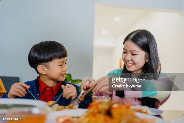 young sibling eating chinese new year family reunion dinner at home - asian food stock pictures, royalty-free photos & images