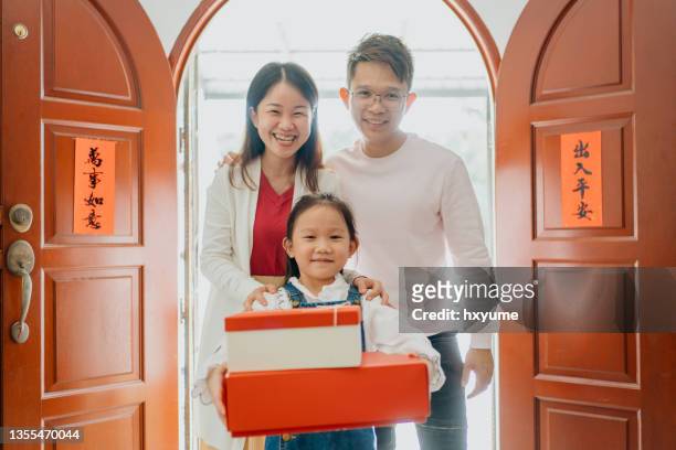 smiling young girl carrying gift box while visiting relatives during chinese new year - carrying gifts stock pictures, royalty-free photos & images
