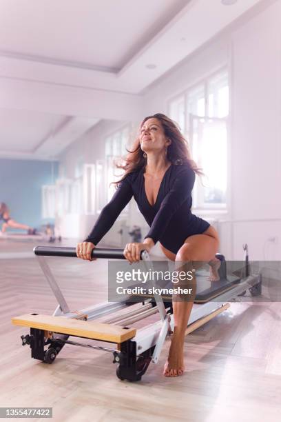 glückliche reformerin, die auf einer pilates-maschine trainiert. - reformer stock-fotos und bilder