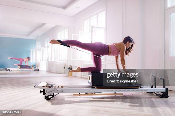 glückliche athletische frau, die auf einer pilates-maschine trainiert. - pilates gerät stock-fotos und bilder