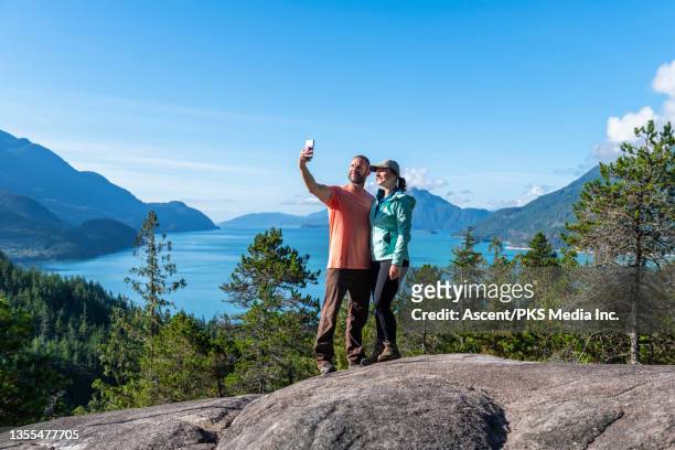 hiking couple relax on sunny coastal mountain ridge - 40s couple sunny stockfoto's en -beelden