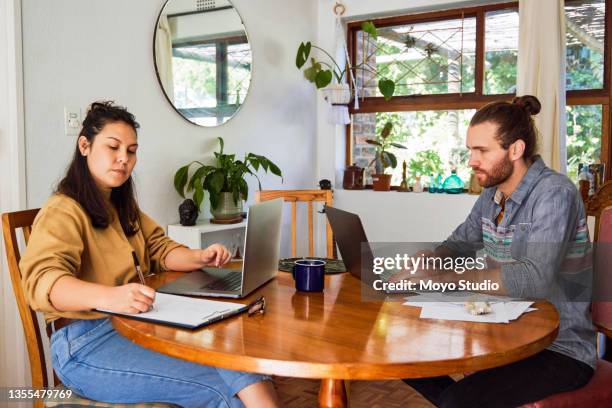 shot of a young couple using laptops and working together at home - debt free stock pictures, royalty-free photos & images