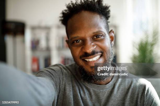 smiling young man having online conference from home - jobs film stockfoto's en -beelden