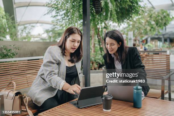 transgender female working on laptop with colleague at outdoor. - smart casual lunch stock pictures, royalty-free photos & images