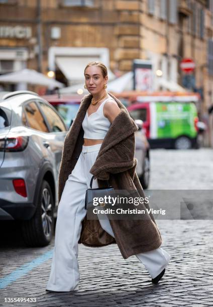 Sonia Lyson is seen wearing white cropped top and pants, jewellery Seezona, Max Mara coat, Balencaiga bag on November 24, 2021 in Rome, Italy.