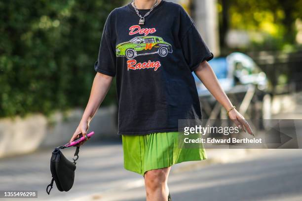 Lolo Zouaï wears a silver and rhinestones large chain necklace with a locker pendant, a dark gray t-shirt with a green car print pattern and red...
