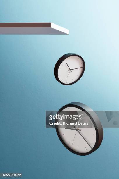 two clocks falling from a shelf - uhr stock-fotos und bilder