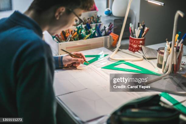 medium shot of teenager boy doing maths homeworks at home - ruler desk stock pictures, royalty-free photos & images