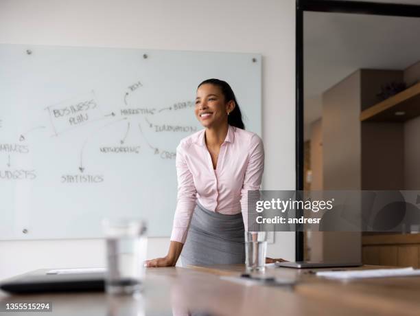 happy business woman leaning on a table at the office and smiling - office leaning stock pictures, royalty-free photos & images