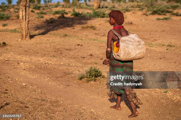 afrikanische junge frau, die wasser aus dem brunnen trägt, äthiopien, afrika - hamar stock-fotos und bilder