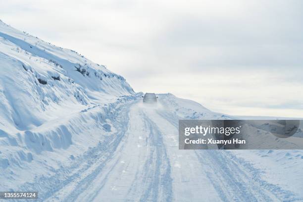 the car is driving on the snow-covered road - snowfield fotografías e imágenes de stock