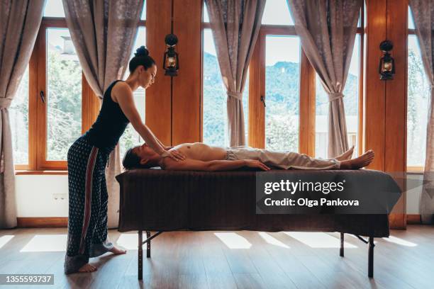 female massage therapist while working in a cozy wooden hall. massage, relaxation, spa, body care, antistress, aromatherapy. - マッサージ台 ストックフォトと画像