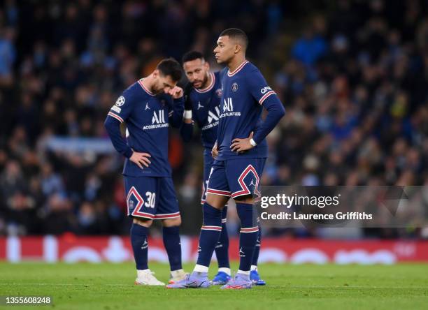 Kylian Mbappe of Paris Saint-Germain looks on as teammates Lionel Messi and Neymar talk in the background after Manchester City's first goal during...