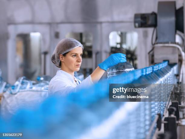 technologist in bottling factory checking water bottles before shipment. - bottling plant stock pictures, royalty-free photos & images