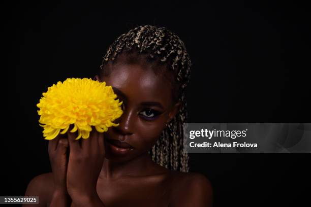 portrait of beautiful afro woman with flower - cornrow braids stock-fotos und bilder