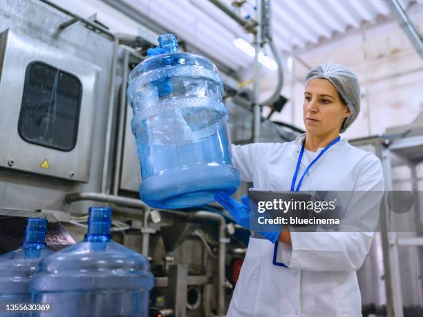 technologist in bottling factory checking water bottles before shipment. - gallon stock pictures, royalty-free photos & images