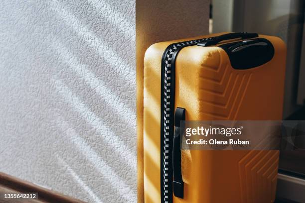 yellow suitcase near white wall. - luggage trolley stock-fotos und bilder