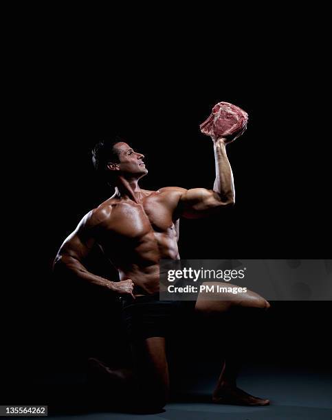 bodybuilder posing with meat - masculinidade imagens e fotografias de stock