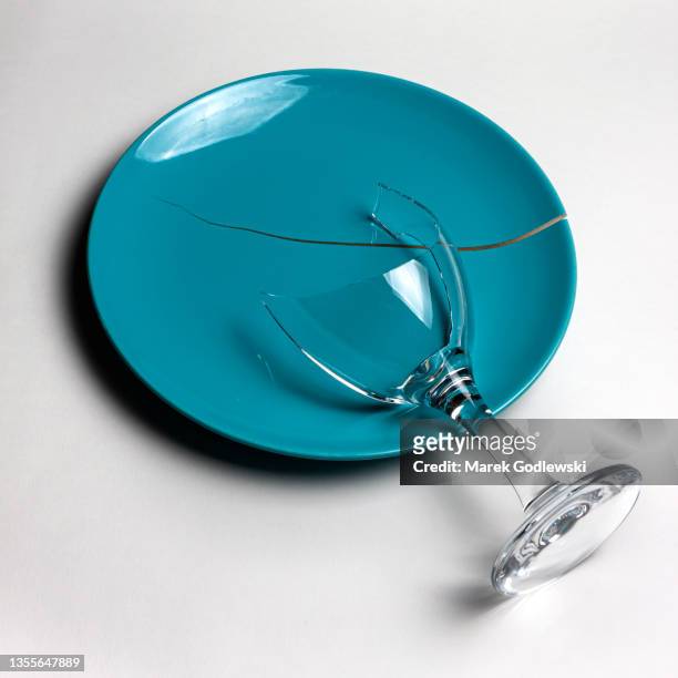 shattered, broken wine glass and crack in blue plate on white background, rift between two parts - assiette cassée photos et images de collection