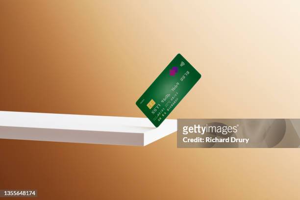 a debit card balanced on the edge of a shelf - credit card stock-fotos und bilder