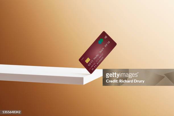 a debit card balanced on the edge of a shelf - credit risk stock pictures, royalty-free photos & images
