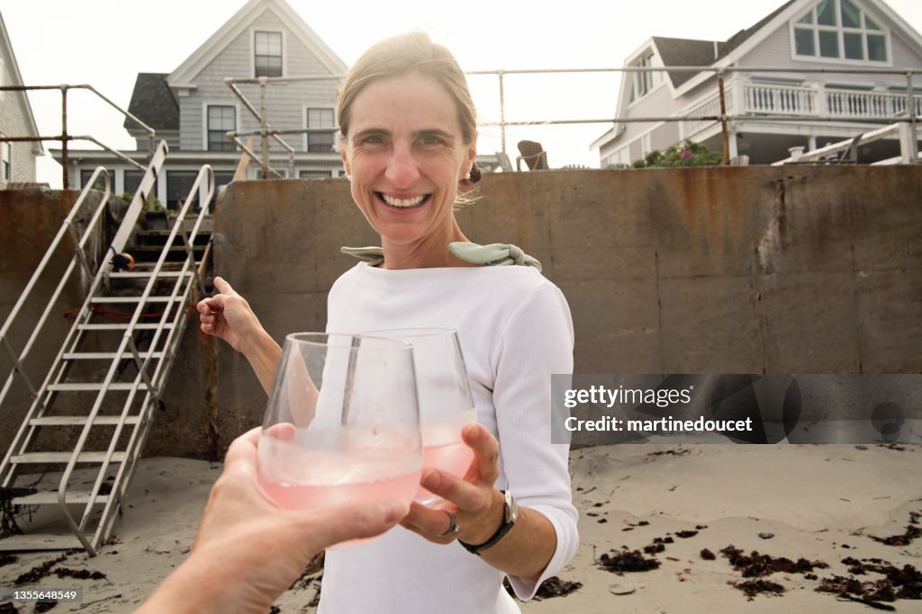 Woman having a drink in front of her house on the beach.