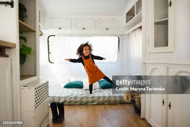 happy afro girl dancing on the bed. - girl in yellow dress stock pictures, royalty-free photos & images