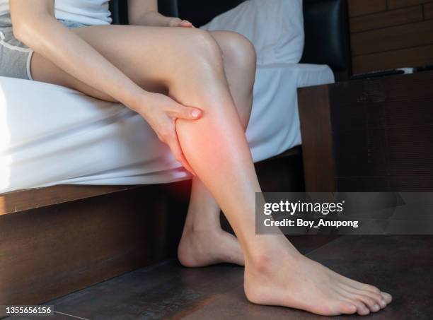 close up of woman hand holding and massage her calf caused of suffering from calf pain. - adult woman legs close up stock-fotos und bilder