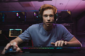 Man wearing headset sitting in front of the computer and being involved at the game