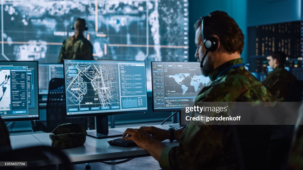 Military Surveillance Officer Working on a City Tracking Operation in a Central Office Hub for Cyber Control and Monitoring for Managing National Security, Technology and Army Communications.