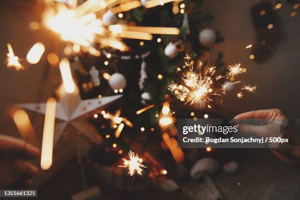 happy new year,cropped hands of person holding illuminated sparklers at night - bengal new year stock pictures, royalty-free photos & images