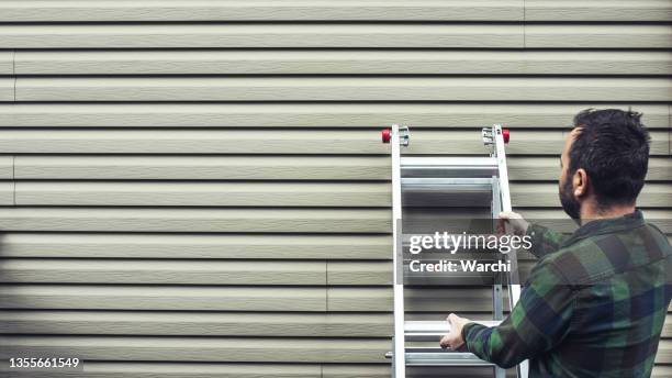 house owner installing a ladder to inspect the wall siding - ladder imagens e fotografias de stock